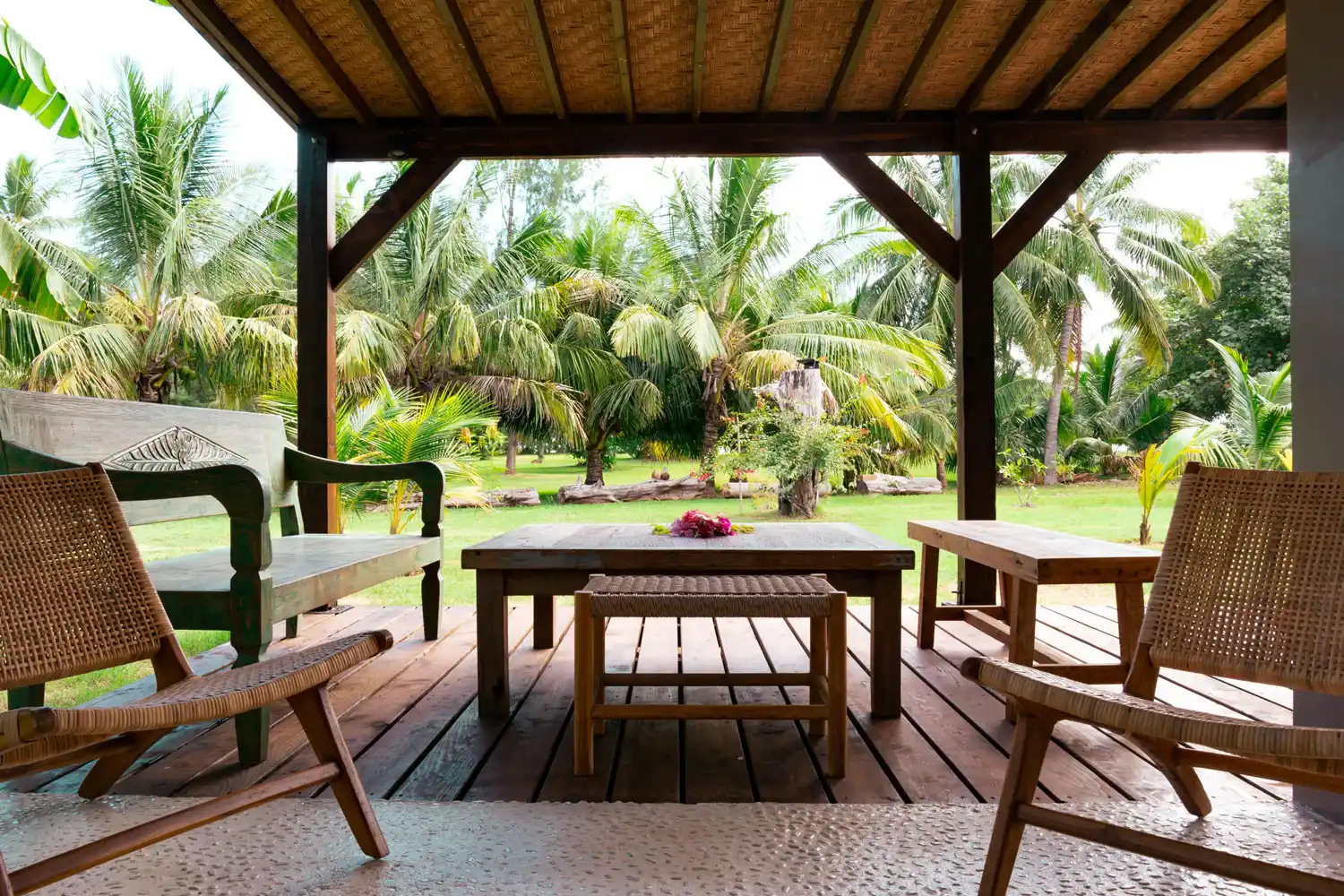 View from the outdoor terrace of Fare Kautinaki, immersed in a lush garden and equipped with luxury wooden furniture, offering an oasis of tranquility and elegance.