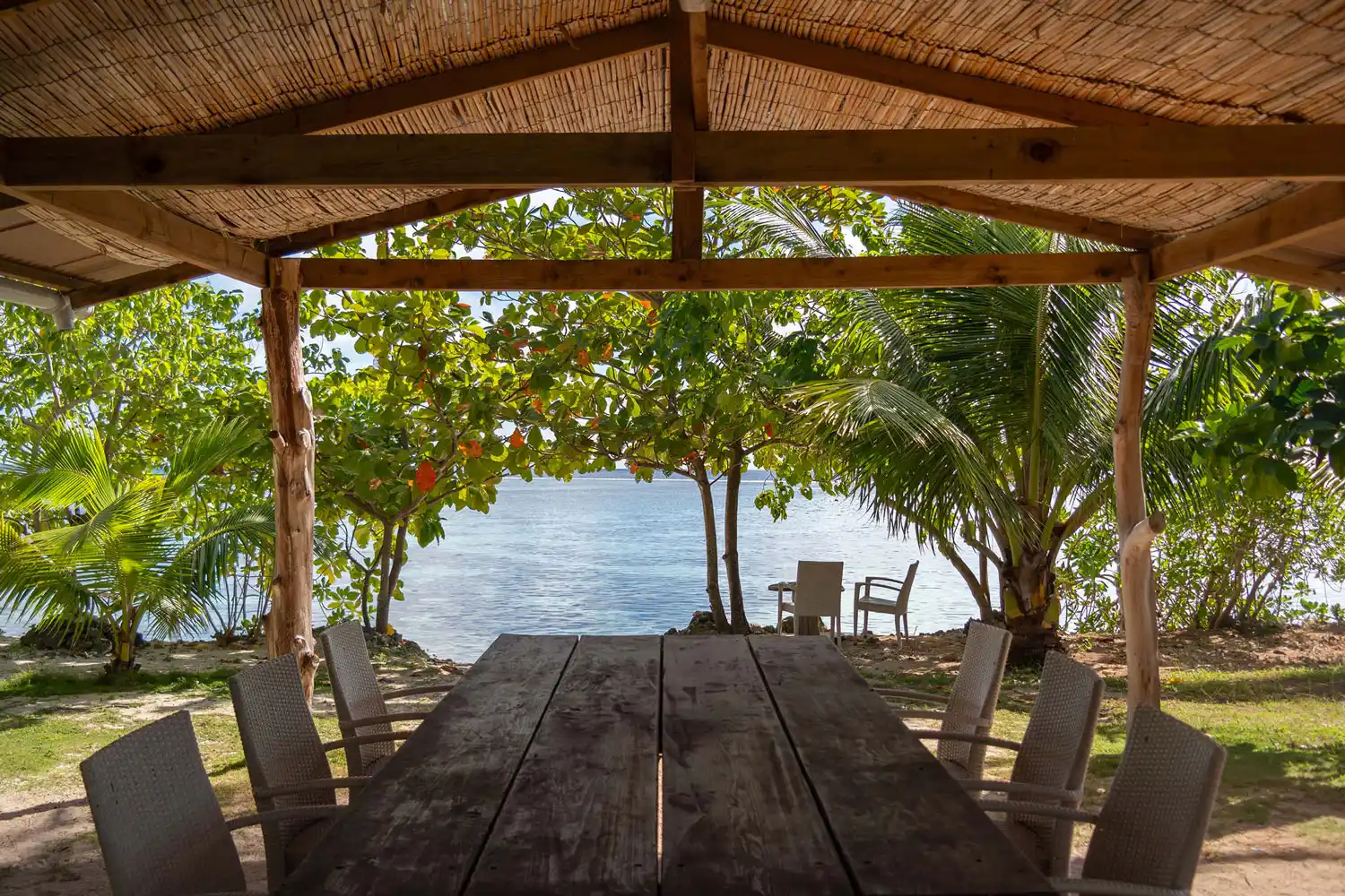 Table à manger extérieure nichée parmi la végétation luxuriante, avec vue imprenable sur le bord du lagon à Fare Tiaia Moorea.