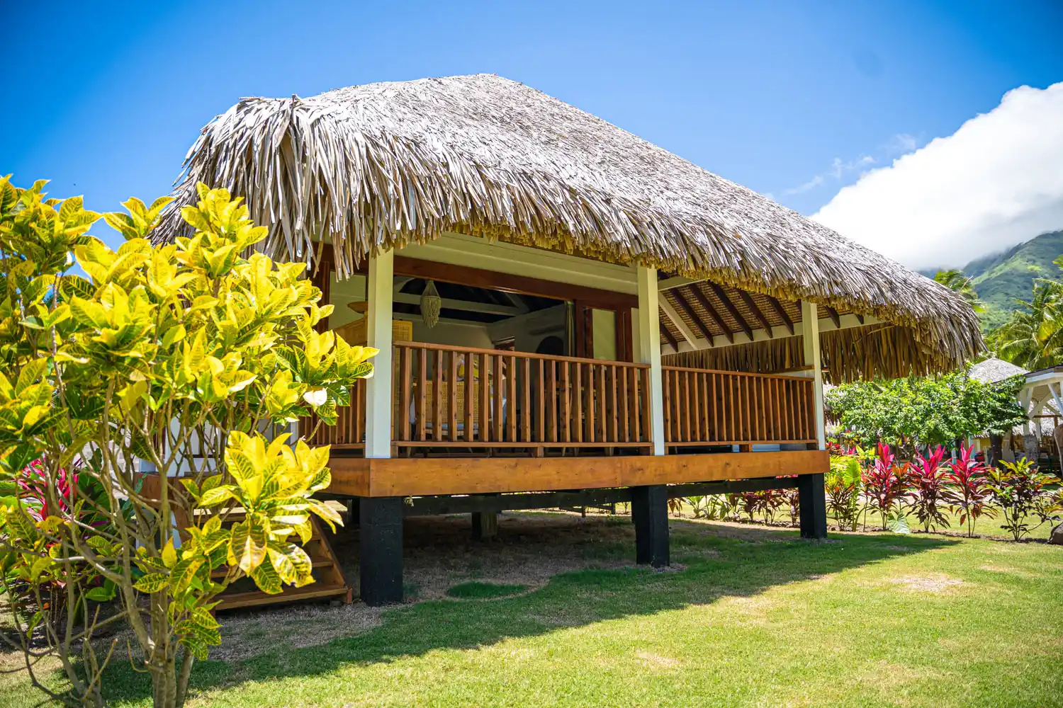 Tropical bungalows at Fare Tiaia, Moorea with traditional Polynesian roofs offering a breathtaking view of the surrounding mountain.