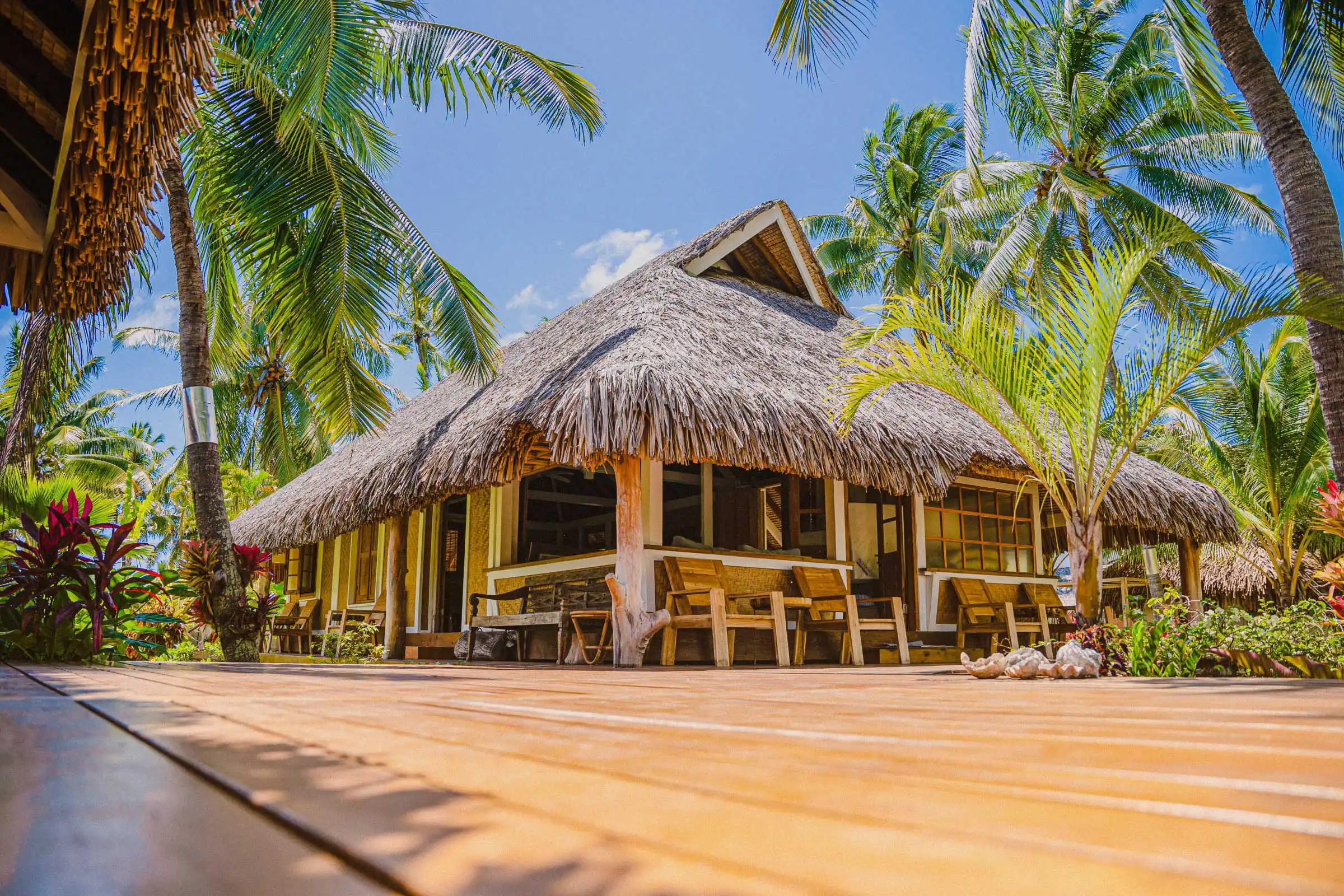 Vue extérieure du Faré Amuï avec son deck inspiré des habitations polynésiennes, entouré de végétation et agrémenté de mobilier en bois, à Fare Tiaia Moorea.