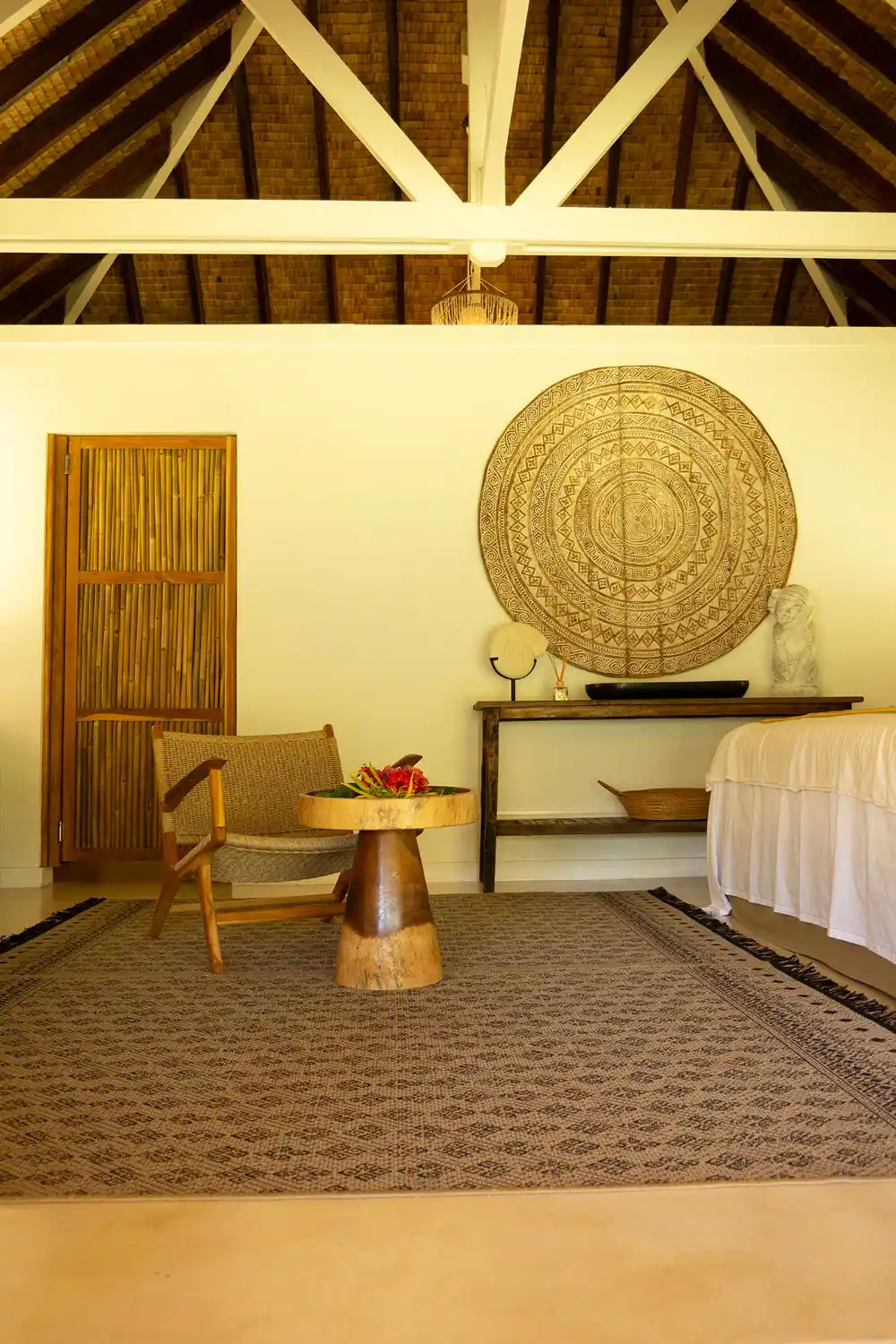 Intimate details of the bungalow's bedroom at Fare Tiaia Moorea, adorned with elegant Balinese decor, inviting relaxation and escape.