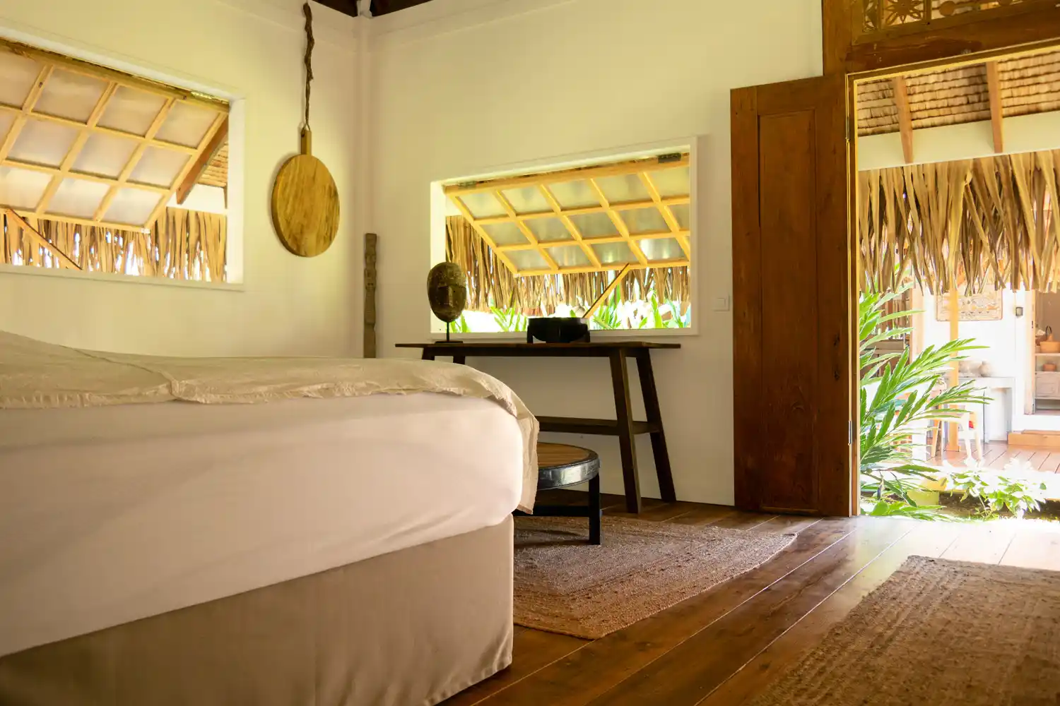 Polynesian-themed bedroom opening onto an outdoor deck surrounded by lush vegetation at Fare Tiaia Moorea.